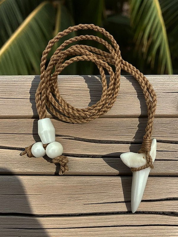 Necklace with brown cord and white shell pendants on a wooden surface