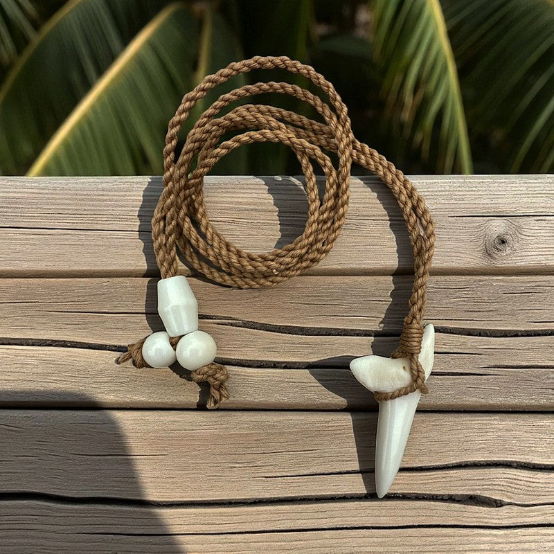 Necklace with brown cord and white shell pendants on a wooden surface