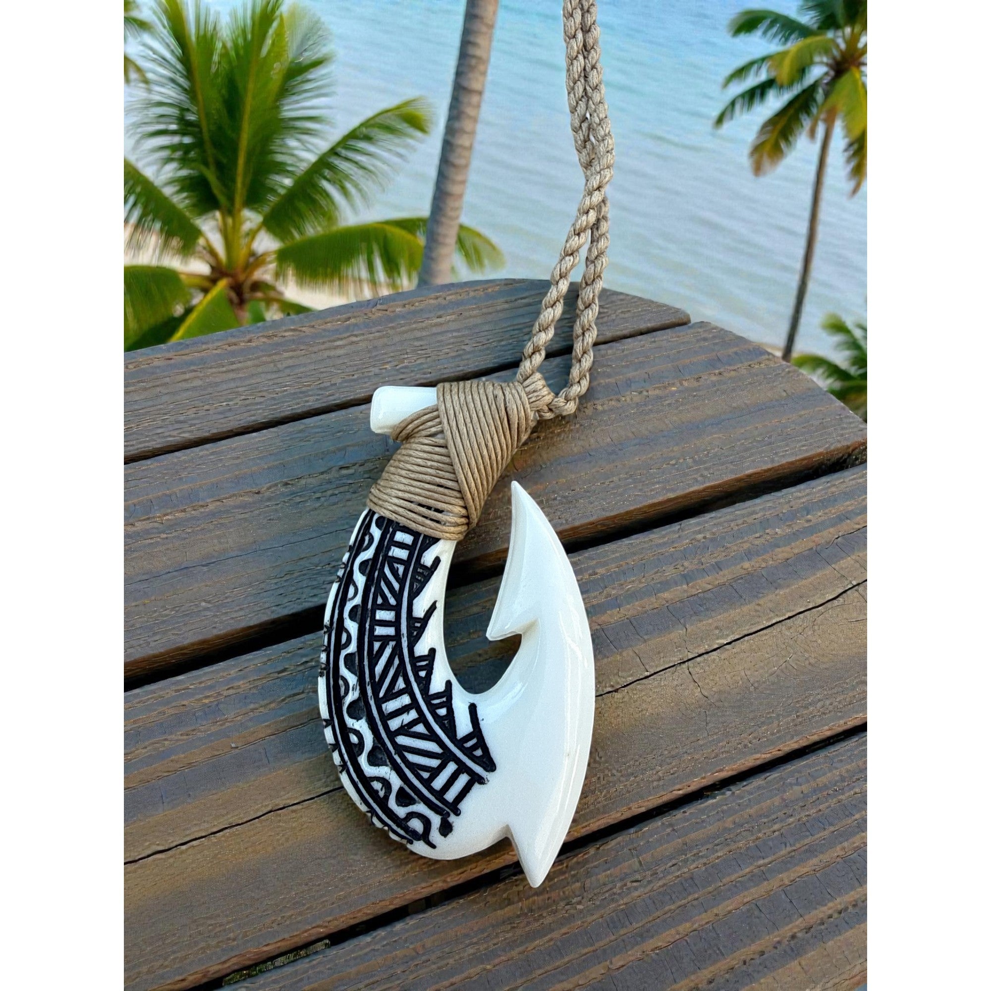 Necklace with fish hook pendant on a wooden surface with palm trees in the background