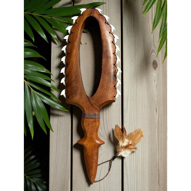 Wooden weapon with a feather on a wooden background