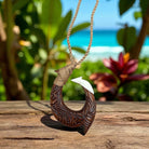 Wooden fish hook pendant on a rope with a tropical background