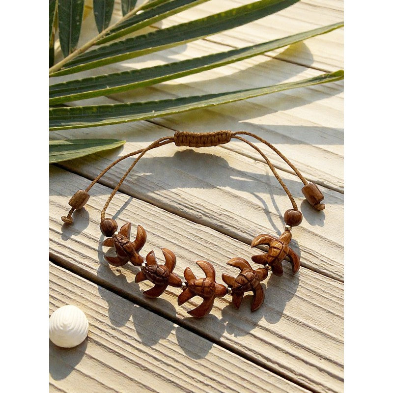 Bracelet with star-shaped brown beads on a wooden surface with palm leaves