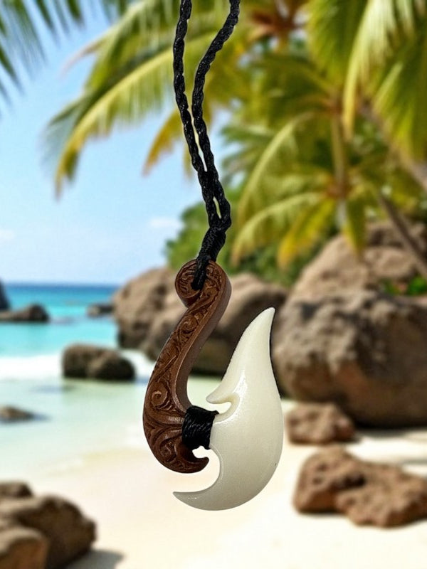 Hook-shaped necklace with carvings on a tropical beach with palm trees and ocean.