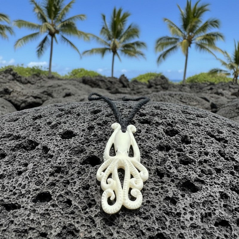 White octopus-shaped necklace on black volcanic rock with palm trees in the background