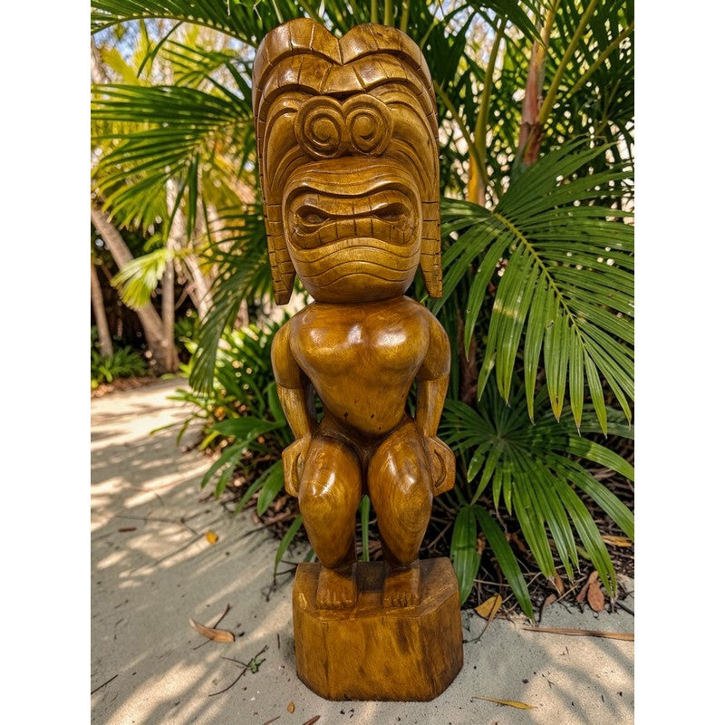 Wooden tiki statue in a tropical setting with palm leaves.