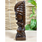 Wooden tiki statue on a light wooden surface with a woven mat background
