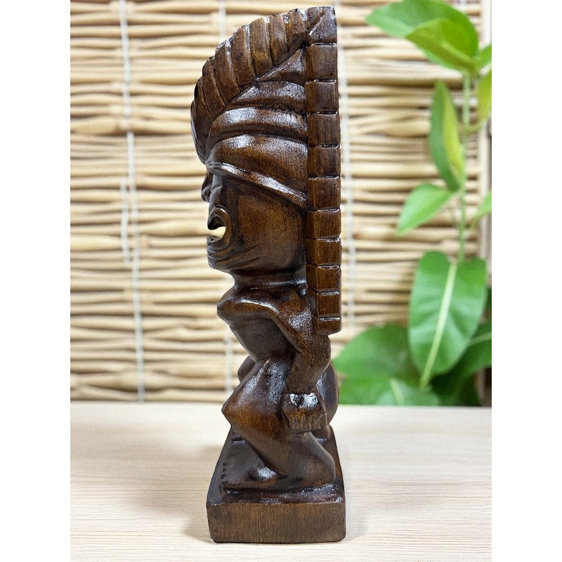Wooden tiki statue on a light wooden surface with a woven mat background