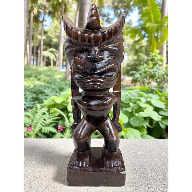 Wooden tiki statue on a stone surface with a garden background