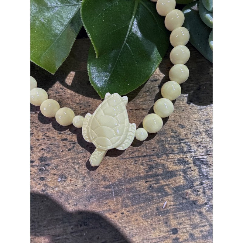 Beaded bracelet with a turtle charm on a wooden surface with leaves in the background