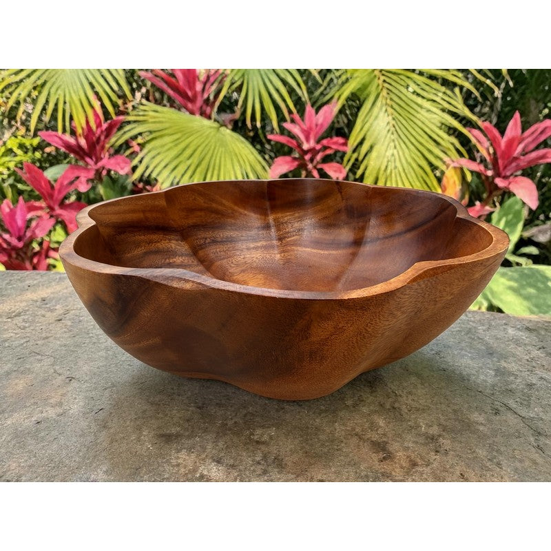 Wooden bowl on a stone surface with tropical plants in the background