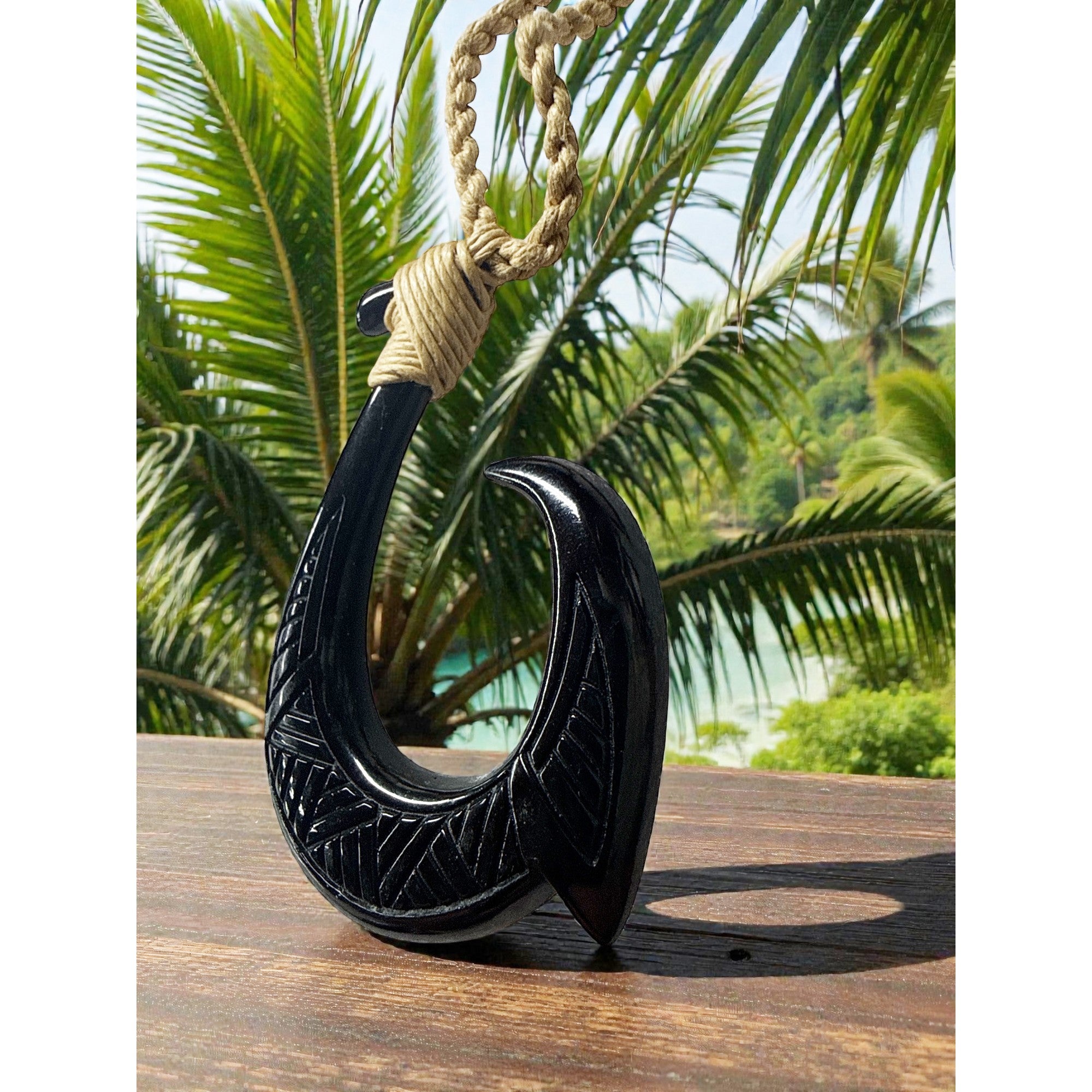Black fish hook with rope against a tropical background