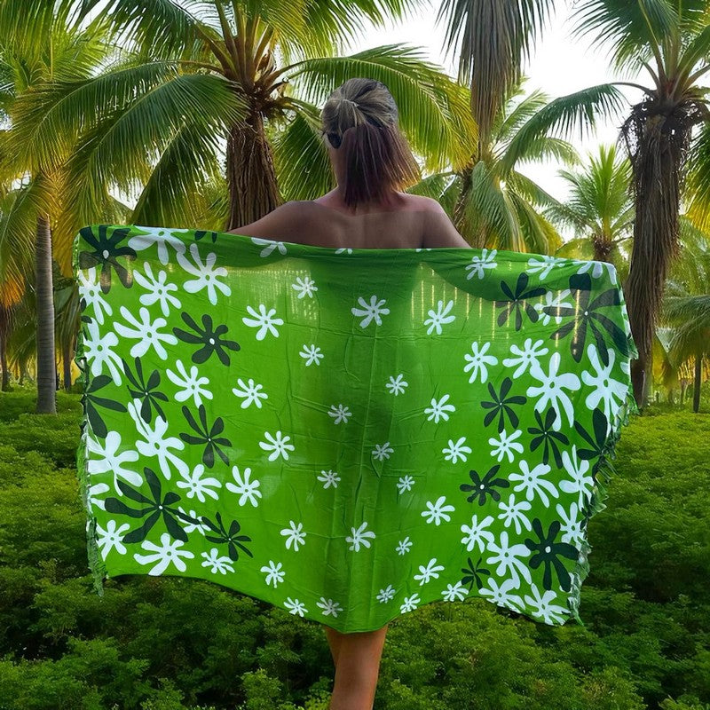 Person wearing a green floral patterned towel in a tropical setting with palm trees.