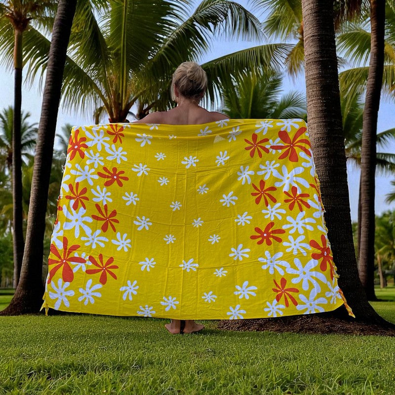 Person holding a yellow floral patterned towel in a tropical setting with palm trees.