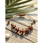 Bracelet with star-shaped brown beads on a wooden surface with palm leaves