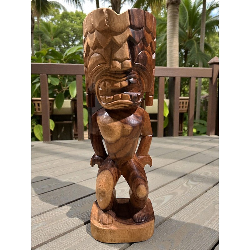 Wooden tiki statue on a wooden deck with a tropical background