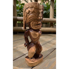 Wooden tiki statue on a wooden surface with blurred greenery in the background