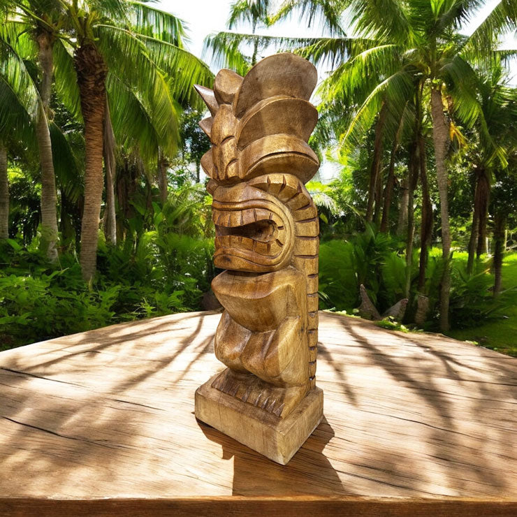 Wooden tiki statue on a wooden platform with palm trees in the background