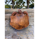Wooden turtle sculpture on a wooden surface with blurred outdoor background