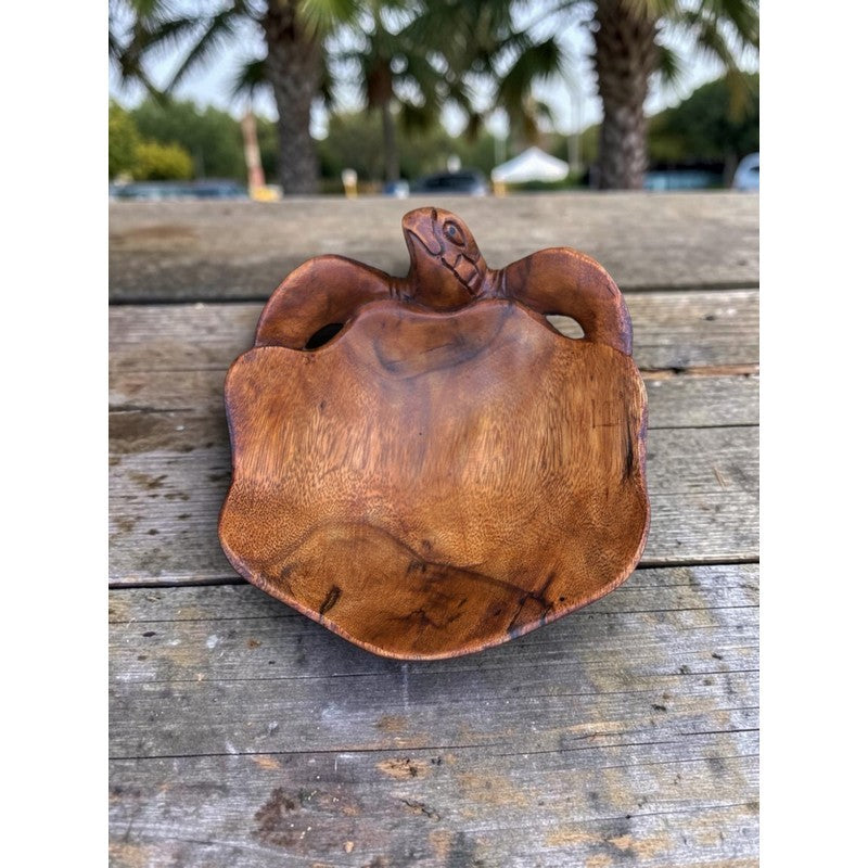 Wooden turtle sculpture on a wooden surface with blurred outdoor background