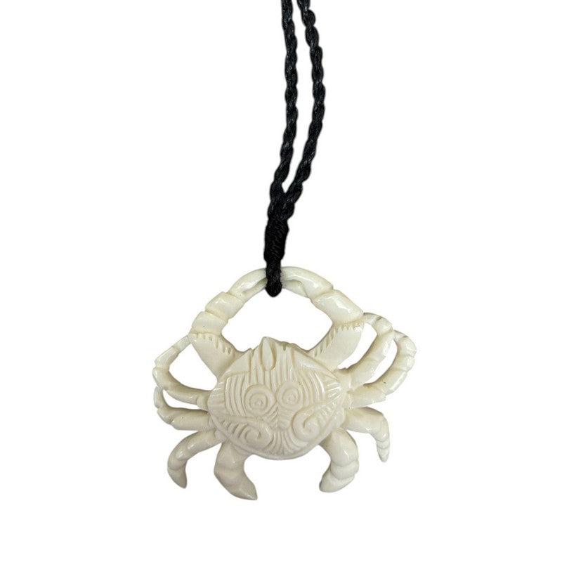 White crab pendant on a black cord against a white background