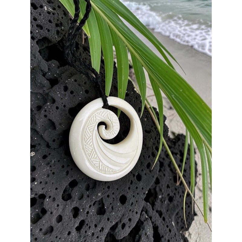 White spiral pendant on a black stone with a beach background
