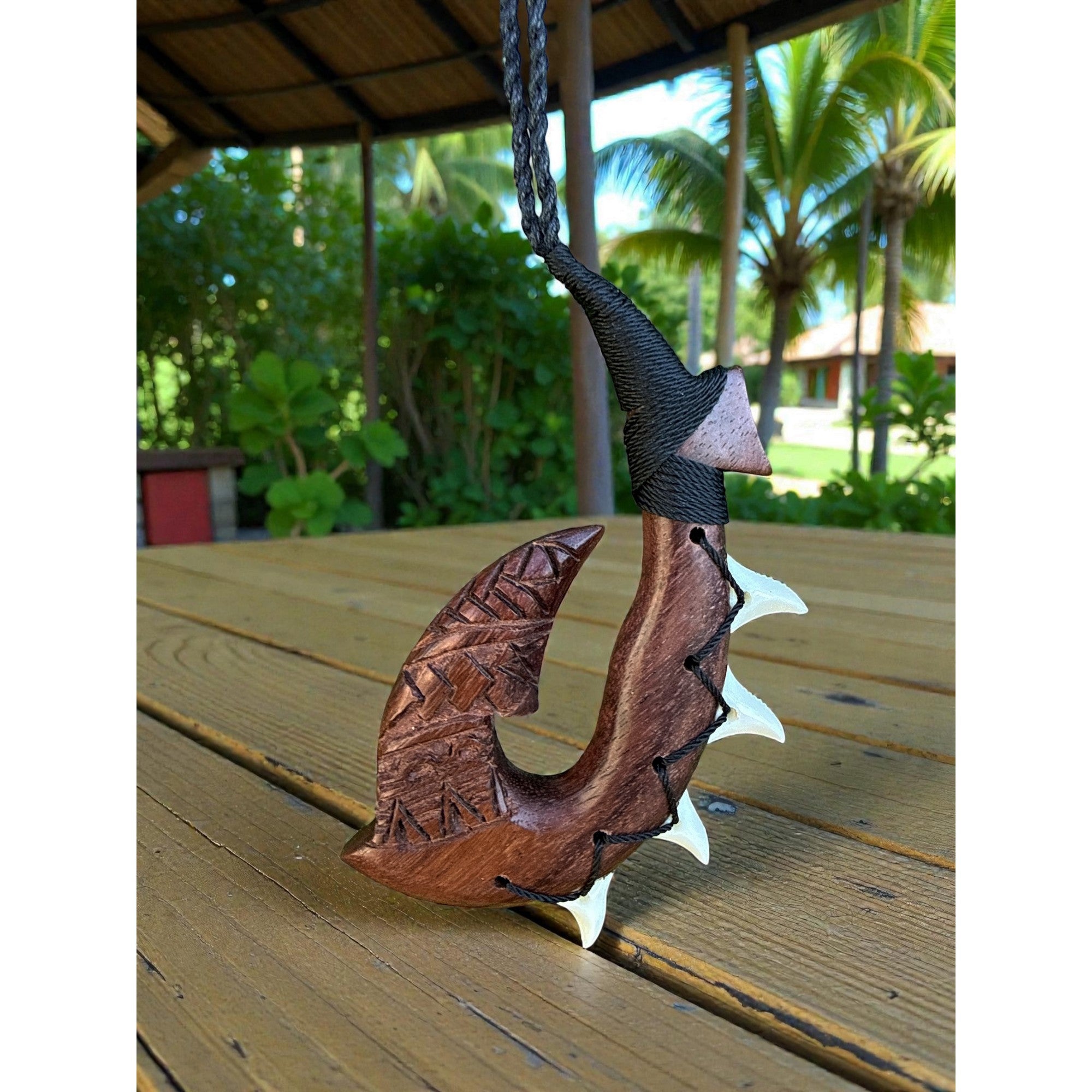 Wooden fish hook ornament on a wooden surface with a tropical background