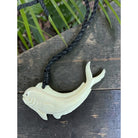 Carved fish pendant on a black cord against a wooden background