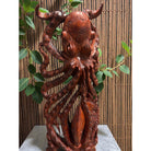 Wooden octopus sculpture with leaves against a bamboo background