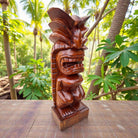 Wooden tiki statue on a table with a tropical background
