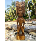 Wooden tiki statue on a beach with palm trees in the background