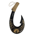 Decorative black fish hook with gold patterns and a string on a white background