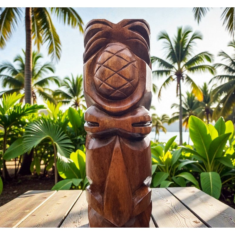 Wooden tiki statue on a wooden platform with tropical plants and palm trees in the background